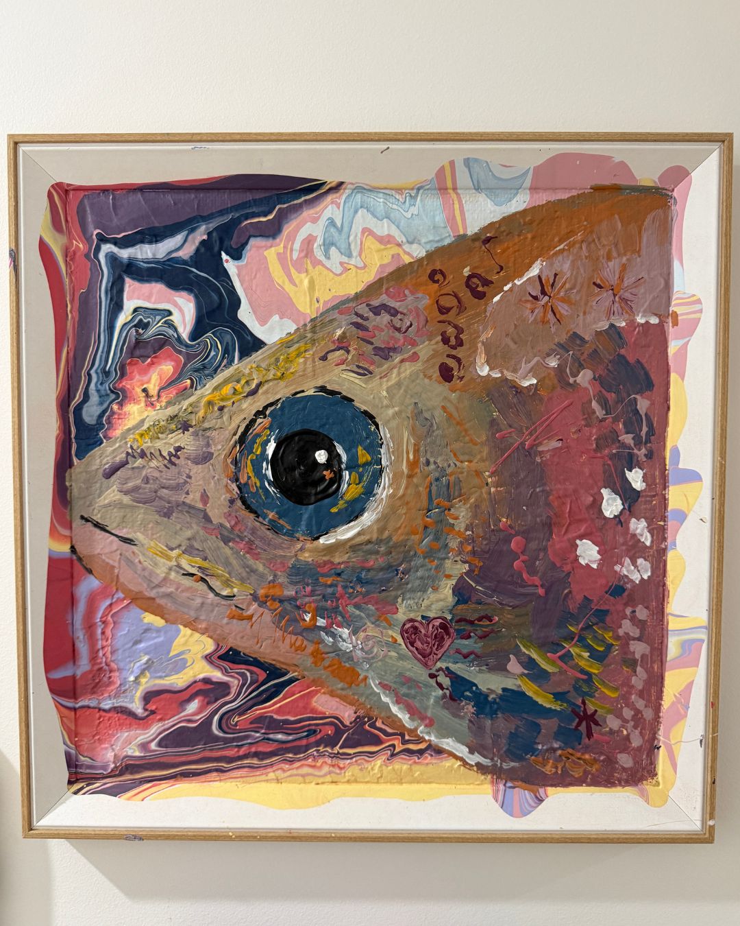 Framed abstract artwork with a colorful fish-like shape on a white wall