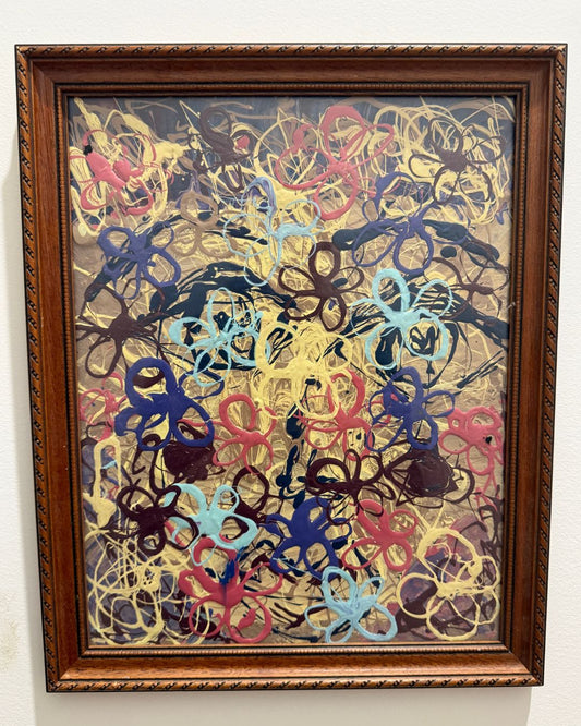 Framed abstract artwork with colorful patterns on a white wall