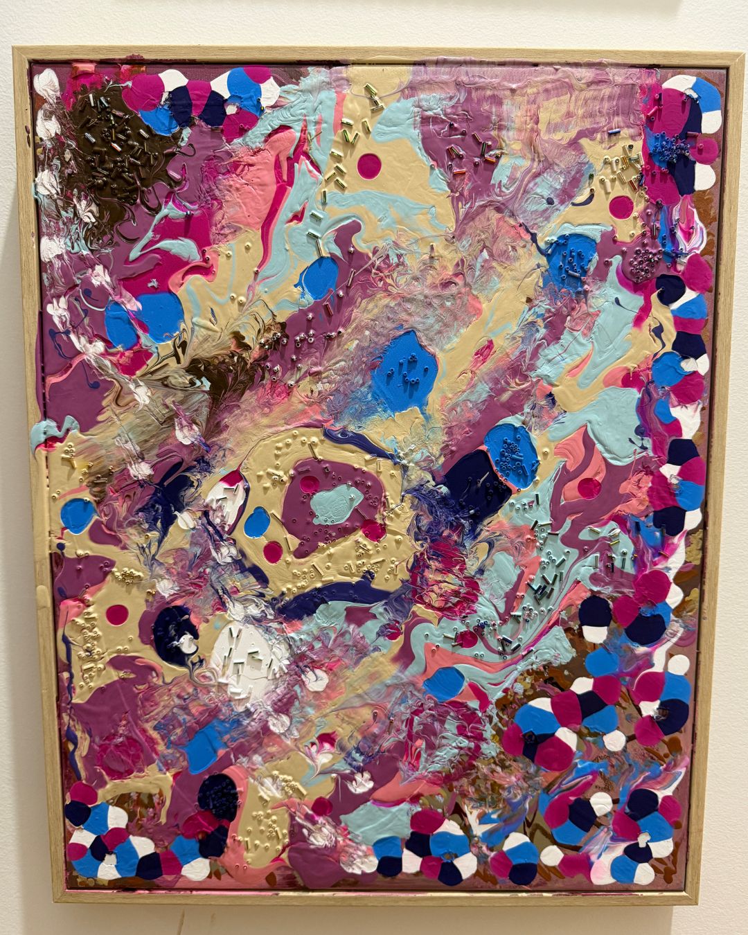 Colorful abstract painting with a timber veneer frame on a white wall