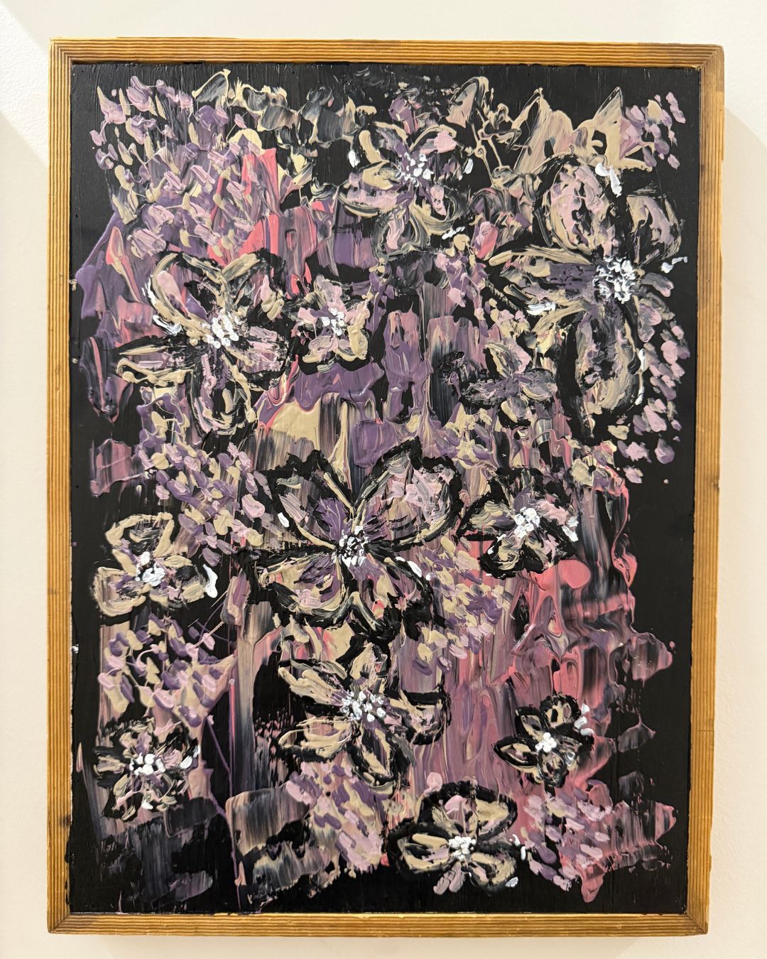 Abstract floral artwork with a wooden frame on a beige wall